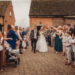 Bride and groom walk through confetti celebration.