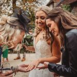 Bride shows wedding ring to friends outdoors