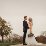 Bride and groom embracing outdoors on wedding day.