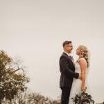 Bride and groom smiling outdoors on wedding day.