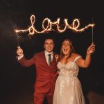 Couple holding sparklers spelling 'love' at night.