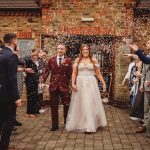 Bride and groom exit through confetti shower.