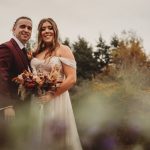 Bride and groom in autumnal outdoor setting.