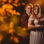 Couple posing in wedding attire, warm golden light.