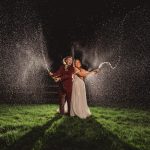 Bride and groom spraying champagne at night celebration.