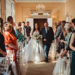 Bride and father walking down aisle at wedding.