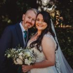 Bride and groom smiling, holding a bouquet.