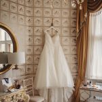 Elegant wedding dress hanging in luxurious dressing room.