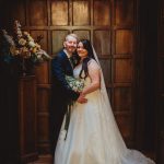 Bride and groom pose in wood-panelled room.