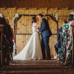 Bride and groom kiss at indoor wedding ceremony.