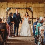 Wedding ceremony in rustic wooden barn setting.