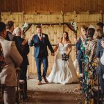 Bride and groom walking down wedding aisle smiling.