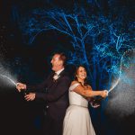 Couple celebrating, spraying champagne outdoors at night.