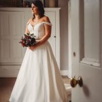 Bride in gown holding bouquet indoors