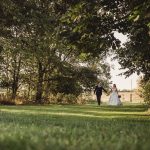 Bride and groom walking in grassy garden