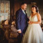 Bride and groom laughing among logs indoors.