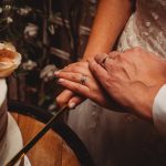 Couple cutting wedding cake together, close-up.