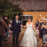 Couple exits wedding ceremony, guests throw confetti.