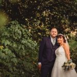 Bride and groom pose in woodland setting