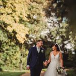 Bride and groom walking in a garden.