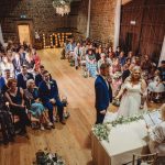 Rustic wedding ceremony with seated guests and couple.