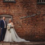 Wedding couple by rustic brick wall