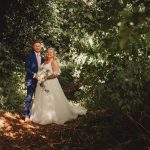 Bride and groom standing in lush forest