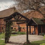 Historic red brick and timber barn entrance in garden.