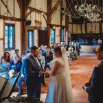 Bride and groom exchanging vows in rustic venue.