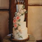 Four-tier wedding cake with flowers and topper