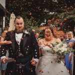 Happy couple celebrates wedding with confetti.