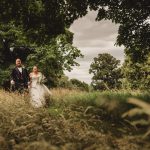 Bride and groom walking in scenic parkland.