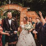 Joyful wedding confetti celebration with couple and guests.