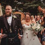 Newlyweds celebrate with guests and confetti shower.