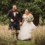 Happy couple walking through park after wedding ceremony.