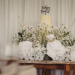 Wedding cake with white floral arrangement on table.