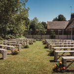 Outdoor garden wedding venue with benches and flowers.