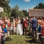 Bride and groom walk down outdoor aisle celebrating.