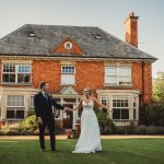 Couple posing outside red brick house