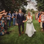 Bride and groom walk through confetti shower.