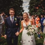 Bride and groom walking through wedding guests outside.