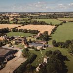 Aerial view of English countryside with fields and buildings.