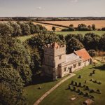 Aerial view of historic church in rural England landscape.