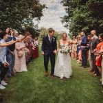 Bride and groom walking through confetti celebration.