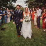 Bride and groom walking, guests throwing confetti.