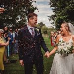 Bride and groom celebrating with guests outdoors.