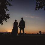 Couple holding hands at sunset, silhouetted scene