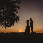 Silhouette of couple at sunset under tree.