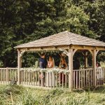 Outdoor wedding ceremony in wooden gazebo with flowers.