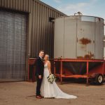 Wedding couple posing by an industrial building.